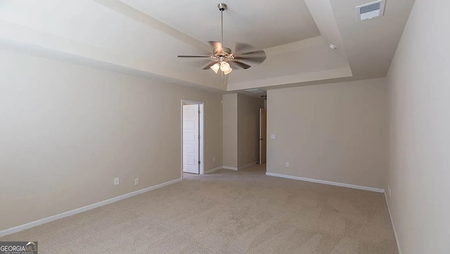 unfurnished room featuring visible vents, baseboards, a raised ceiling, light colored carpet, and ceiling fan