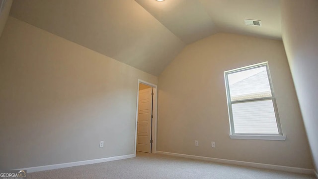 interior space with visible vents, baseboards, light colored carpet, and vaulted ceiling