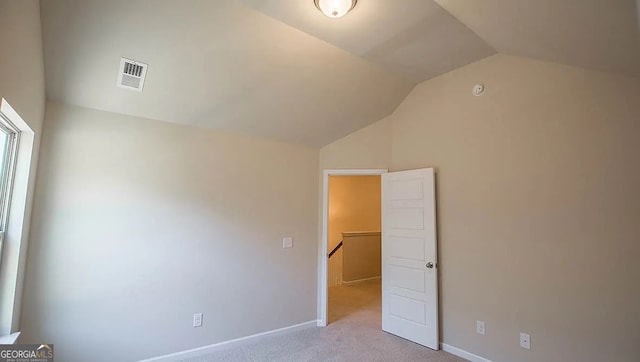 unfurnished bedroom with visible vents, carpet floors, baseboards, and vaulted ceiling