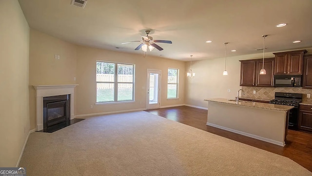 kitchen featuring visible vents, a sink, backsplash, gas range oven, and black microwave