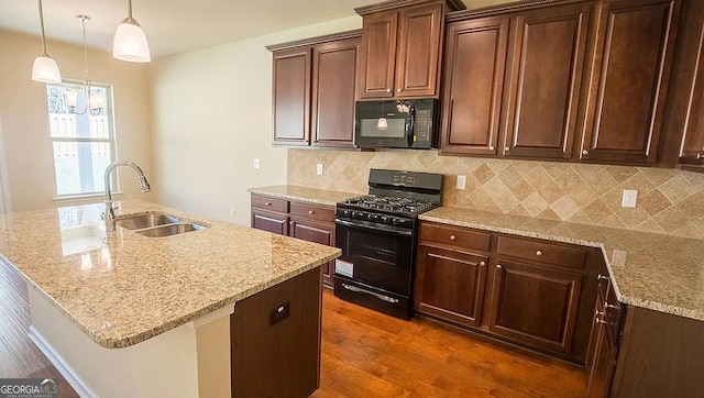 kitchen featuring dark wood-style floors, light stone countertops, a sink, black appliances, and tasteful backsplash