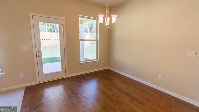 entryway with dark wood-type flooring, a notable chandelier, and baseboards