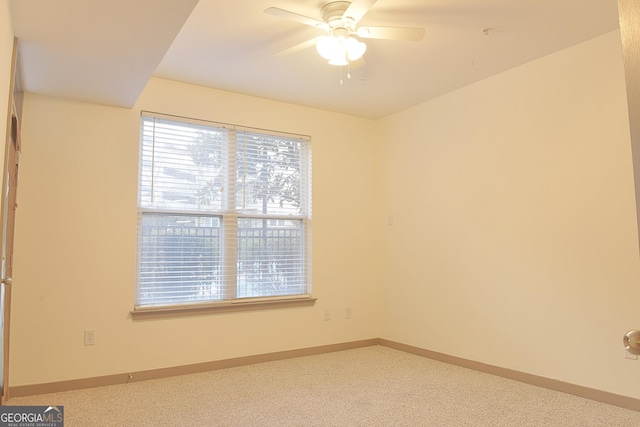 carpeted spare room featuring baseboards and ceiling fan