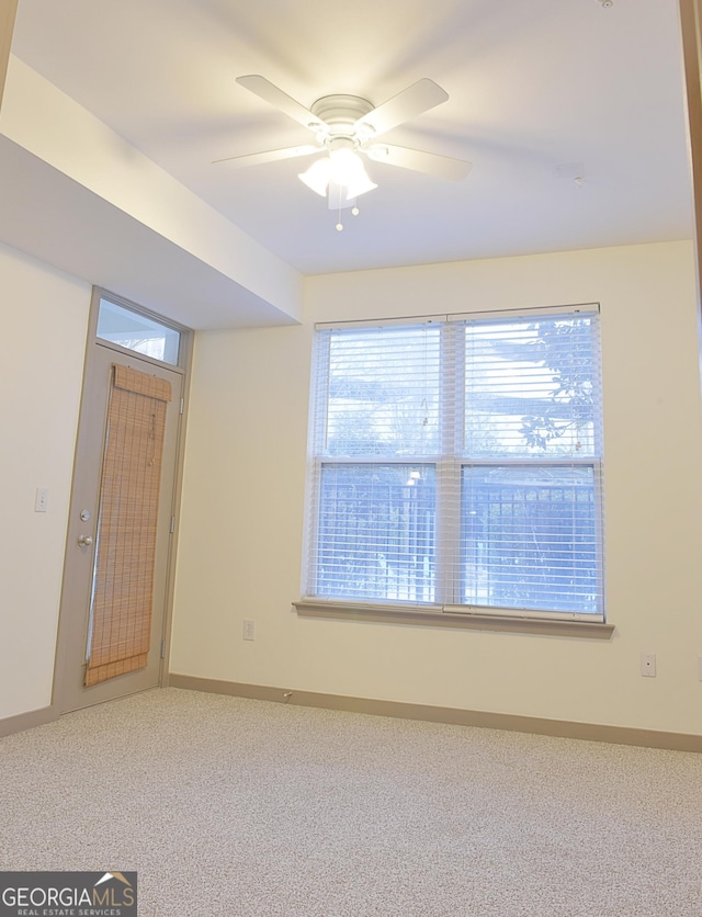 carpeted empty room with baseboards and a ceiling fan