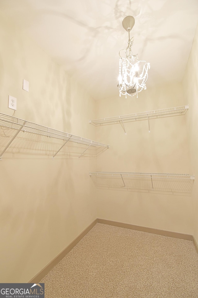 walk in closet with carpet floors and a chandelier