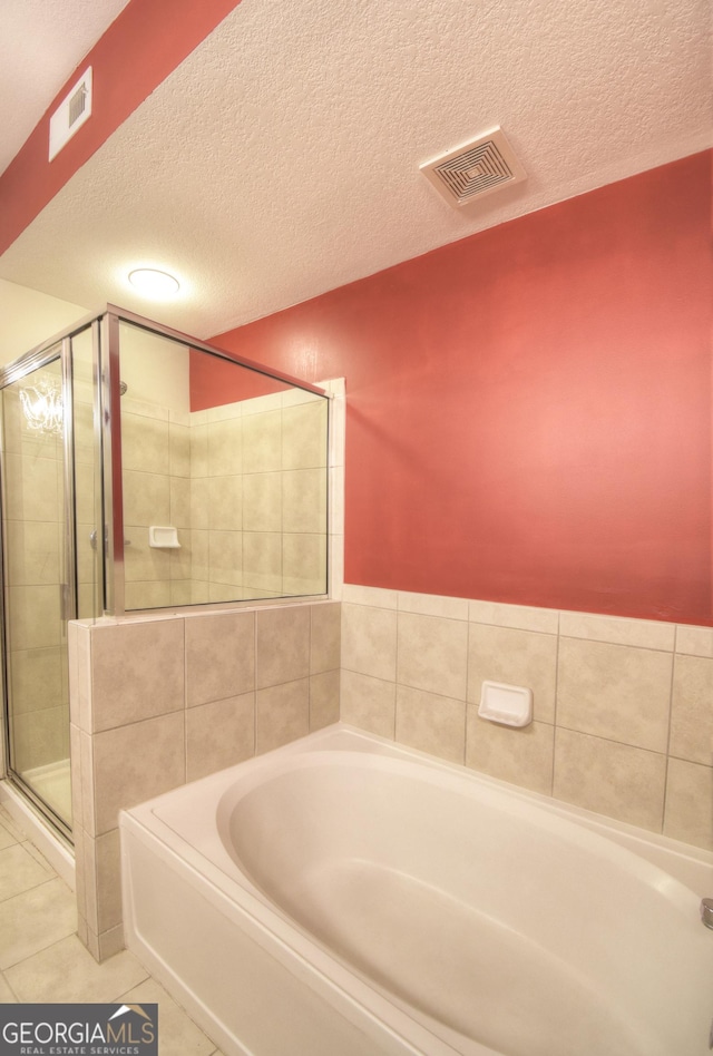 bathroom featuring tile patterned flooring, visible vents, a stall shower, and a garden tub