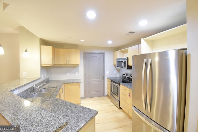 kitchen with light brown cabinetry, a sink, recessed lighting, stainless steel appliances, and a peninsula