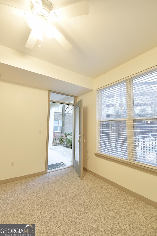 carpeted empty room with a healthy amount of sunlight, baseboards, and ceiling fan