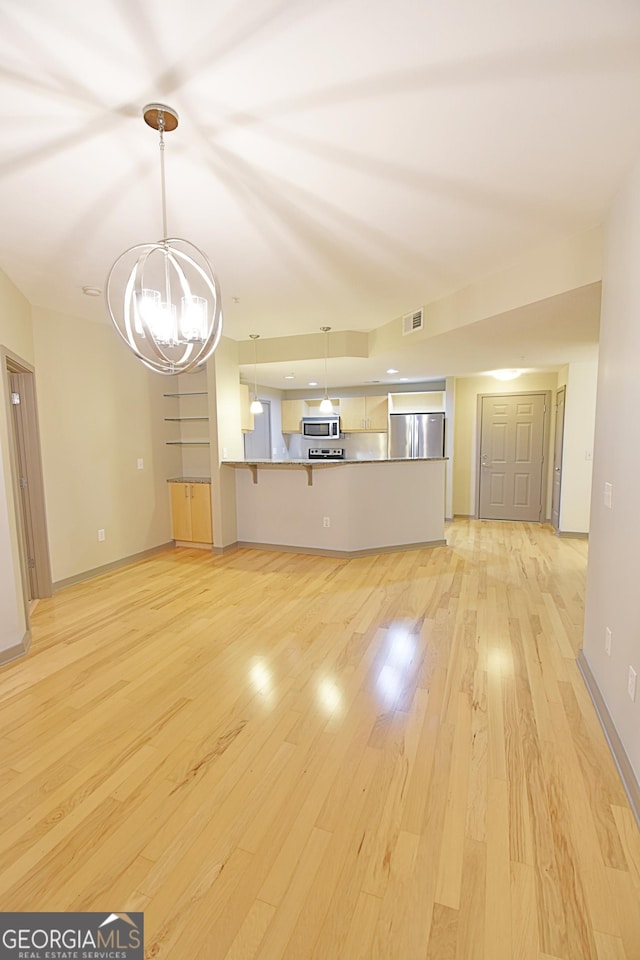 unfurnished living room with visible vents, baseboards, light wood-style floors, and an inviting chandelier