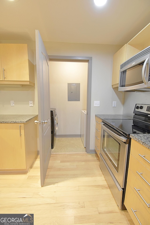 kitchen featuring light wood finished floors, electric panel, light brown cabinetry, stainless steel appliances, and independent washer and dryer