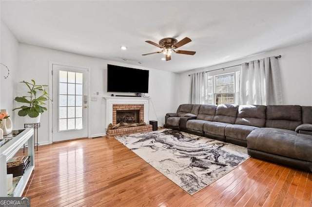 living room with recessed lighting, light wood-style floors, a brick fireplace, and a ceiling fan