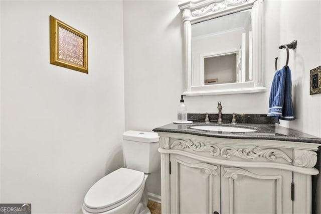 bathroom featuring toilet, ornamental molding, and vanity