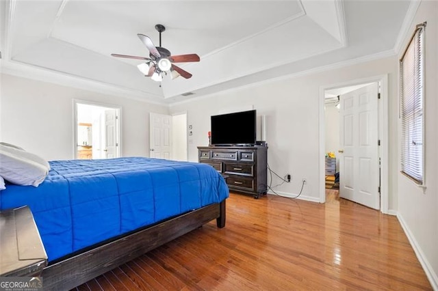 bedroom with baseboards, a raised ceiling, and light wood finished floors