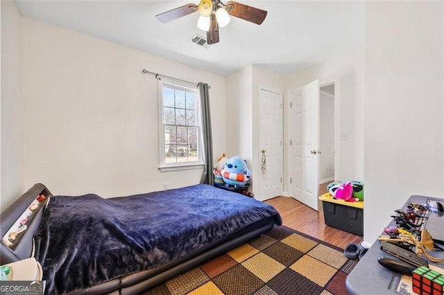 bedroom featuring visible vents, a ceiling fan, and wood finished floors