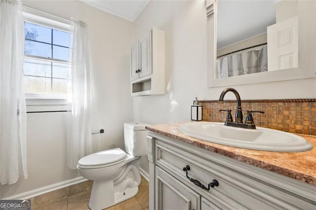 bathroom with vanity, baseboards, decorative backsplash, tile patterned flooring, and toilet