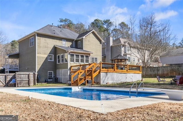 back of property with fence, cooling unit, a wooden deck, a fenced in pool, and stairs