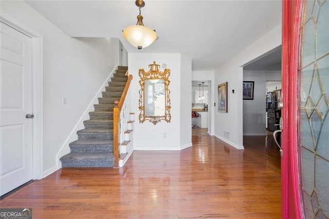 foyer with stairway, visible vents, baseboards, and wood finished floors