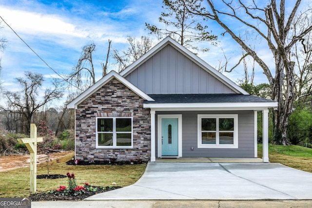 view of front of house featuring stone siding, board and batten siding, and a front lawn