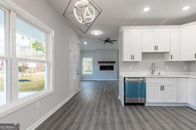 kitchen with baseboards, light countertops, stainless steel dishwasher, white cabinets, and a sink