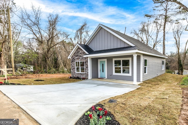 view of front of house with stone siding, board and batten siding, driveway, and a front yard