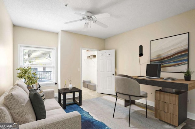 office featuring a textured ceiling, baseboards, and ceiling fan