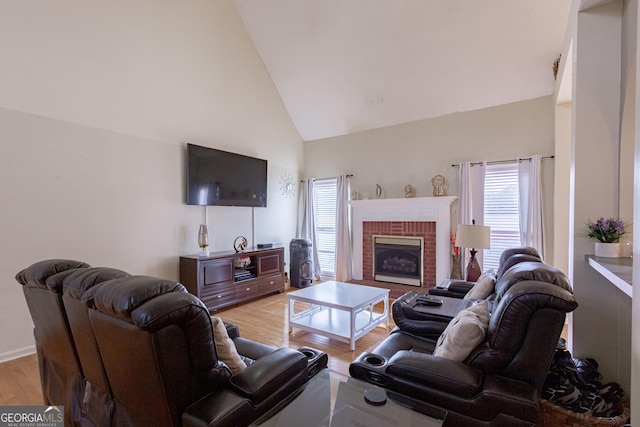 living room featuring a brick fireplace, light wood-style flooring, and high vaulted ceiling