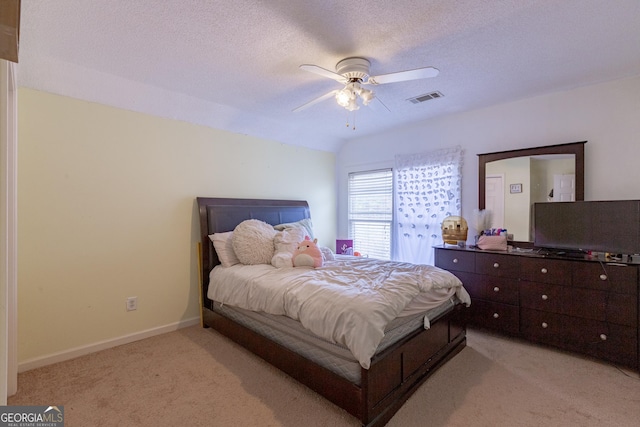 bedroom featuring visible vents, light carpet, a textured ceiling, baseboards, and ceiling fan