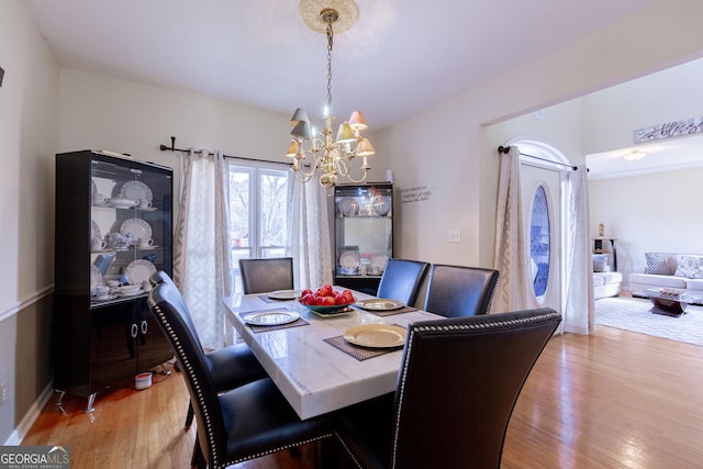 dining space featuring light wood-type flooring and an inviting chandelier