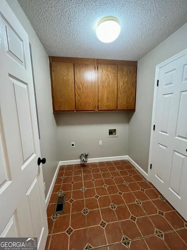 clothes washing area with a textured ceiling, cabinet space, baseboards, and hookup for a washing machine