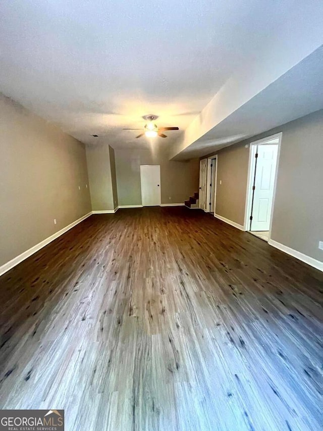 unfurnished living room with a ceiling fan, baseboards, and wood finished floors