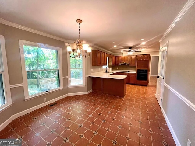 kitchen with light countertops, a peninsula, oven, ornamental molding, and a sink