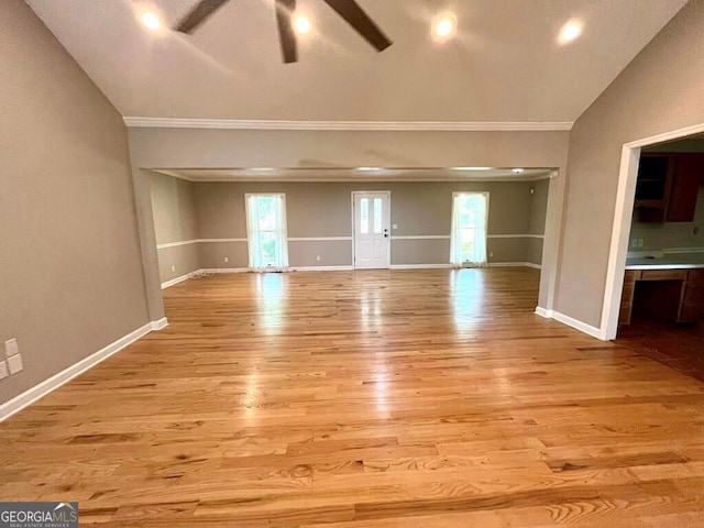 interior space with baseboards, lofted ceiling, light wood finished floors, and ceiling fan