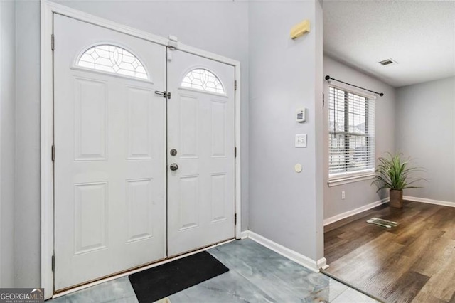 entryway with visible vents, baseboards, and wood finished floors