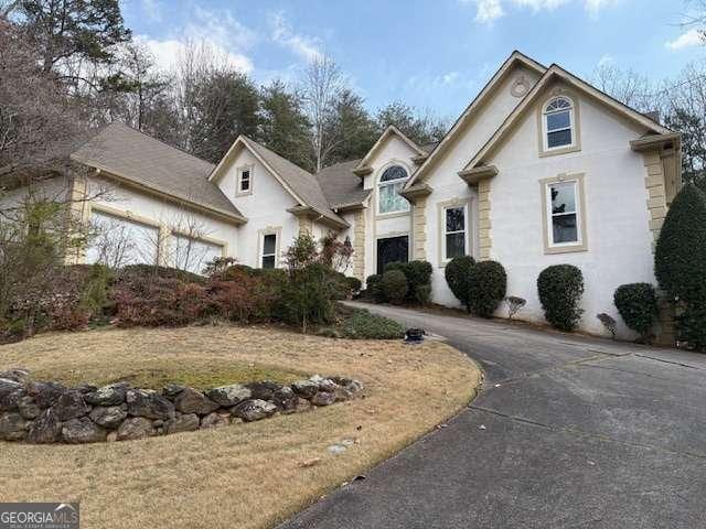 view of front facade featuring an attached garage, driveway, and stucco siding