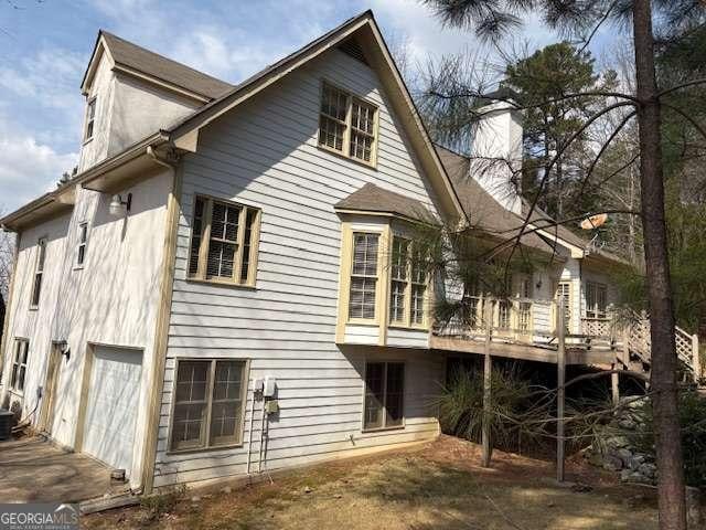 back of property featuring a deck, a garage, and a chimney