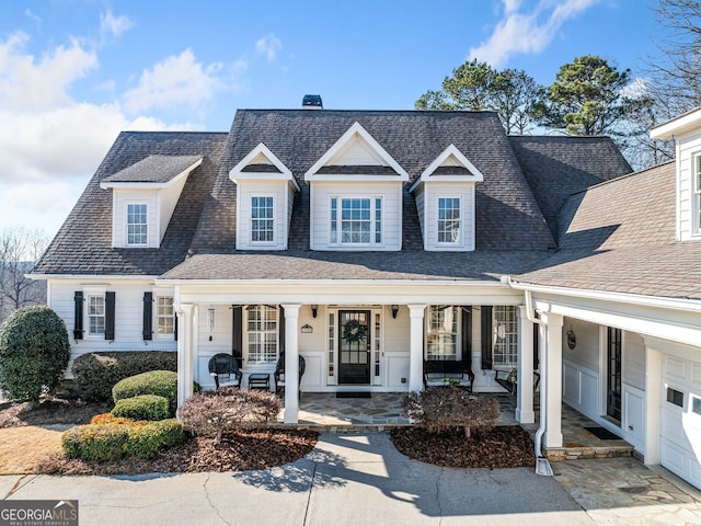 view of front of home with roof with shingles, covered porch, and a chimney