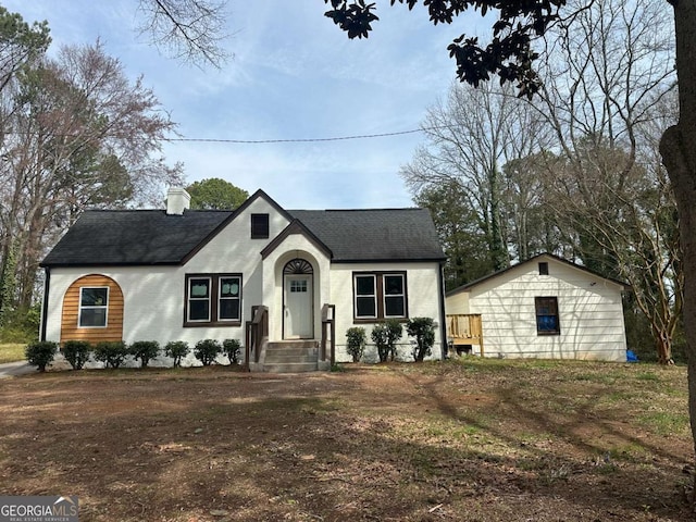 view of front facade with a chimney and a shingled roof