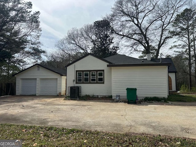 view of property exterior with central air condition unit, an outdoor structure, and roof with shingles