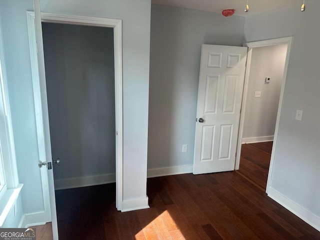 unfurnished bedroom featuring dark wood finished floors and baseboards