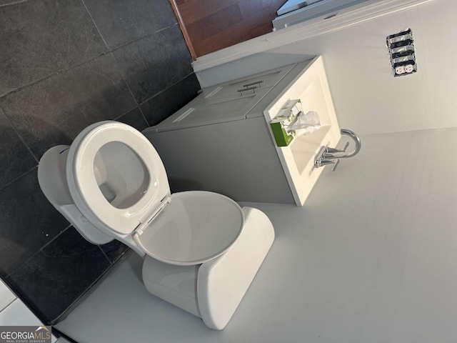 bathroom with tile walls and toilet