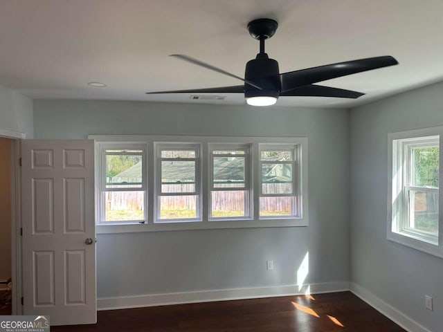 unfurnished room with visible vents, a ceiling fan, baseboards, and dark wood-style flooring