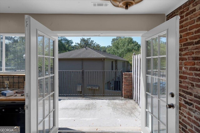 doorway to outside featuring plenty of natural light, brick wall, and visible vents