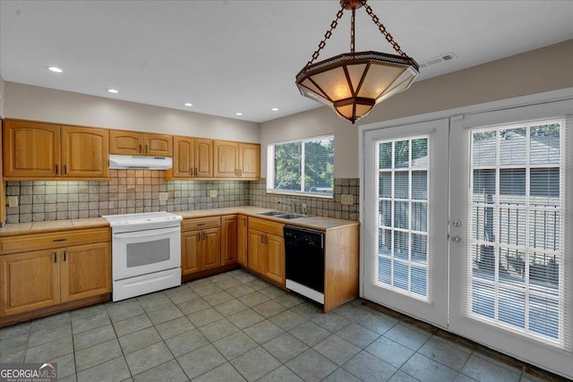 kitchen featuring under cabinet range hood, tile countertops, black dishwasher, electric stove, and a sink