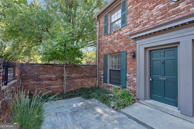 property entrance featuring brick siding and fence