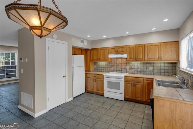 kitchen featuring under cabinet range hood, visible vents, white appliances, and decorative backsplash