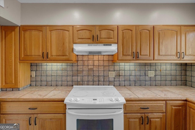 kitchen with decorative backsplash, tile counters, white electric range, and under cabinet range hood