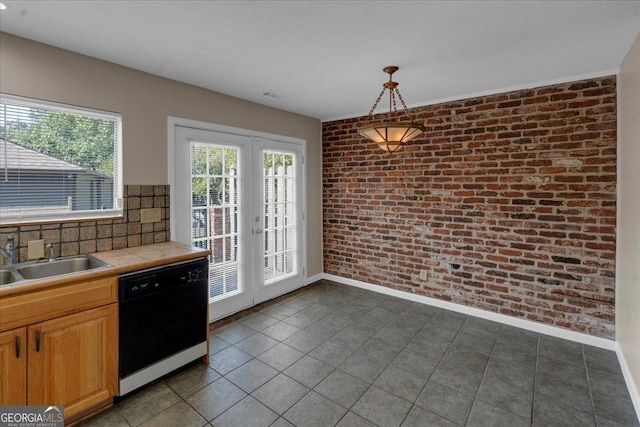 kitchen with tasteful backsplash, brick wall, tile counters, black dishwasher, and a sink