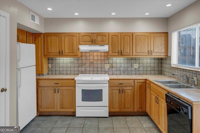 kitchen with visible vents, under cabinet range hood, tile countertops, white appliances, and a sink