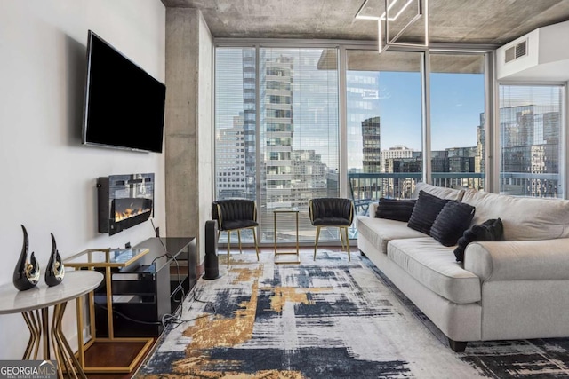 living room with visible vents, floor to ceiling windows, a glass covered fireplace, and wood finished floors