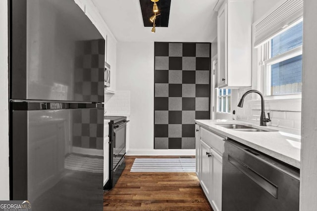 kitchen featuring a sink, dark wood finished floors, white cabinetry, stainless steel appliances, and decorative backsplash